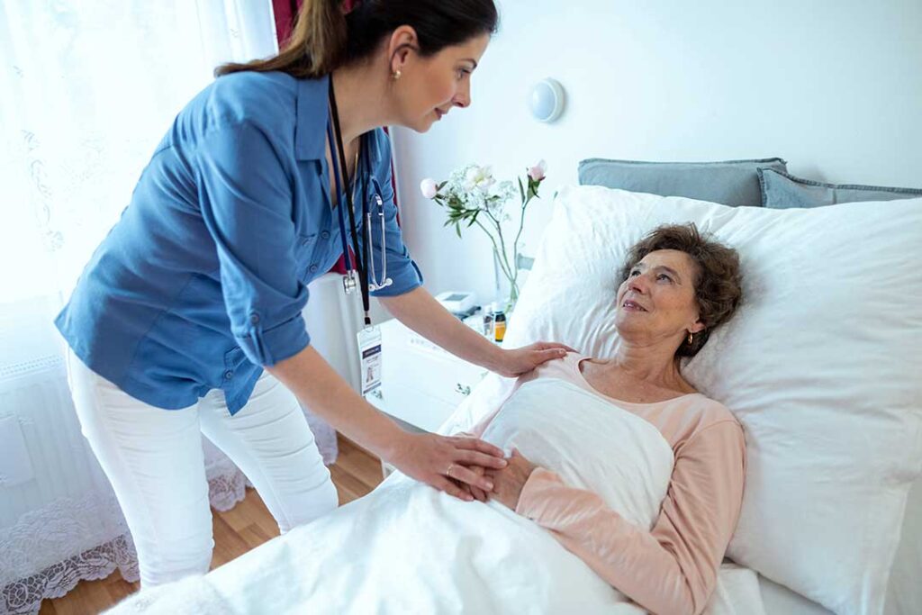 Older adult speaking with a caregiver in a bright assisted living apartment.